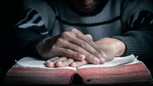 hands on a Bible in prayer 