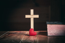 cross and small red heart next to a Bible 