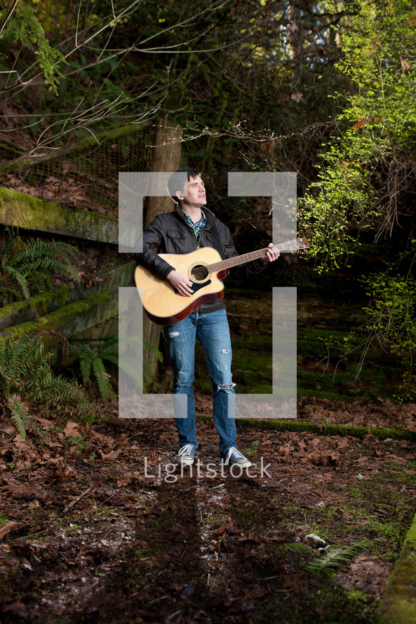 man playing a guitar and singing outdoors