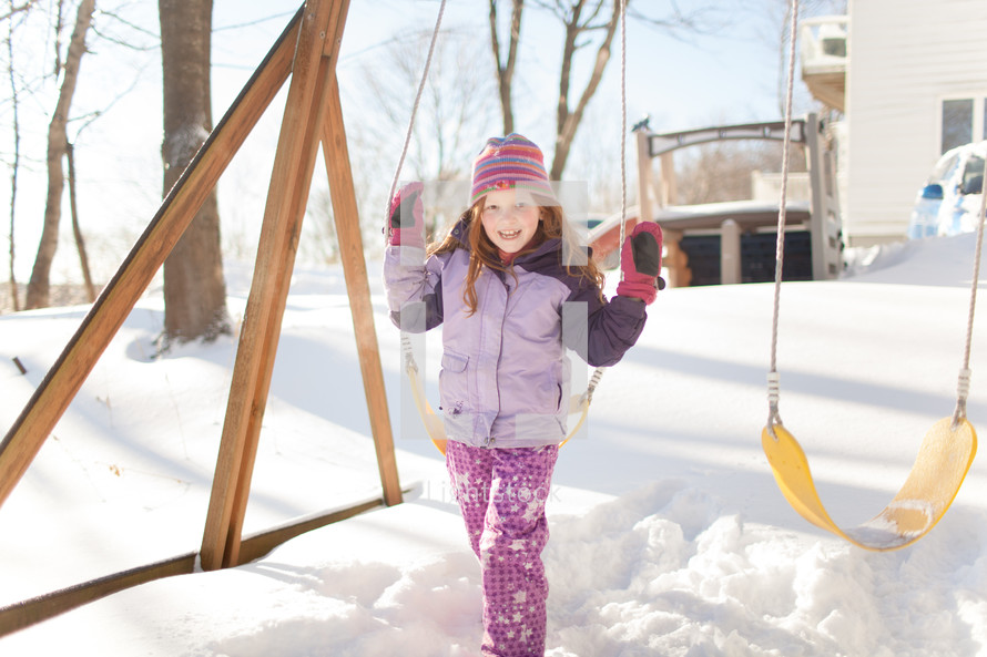 kids playing on a swing set in the snow 