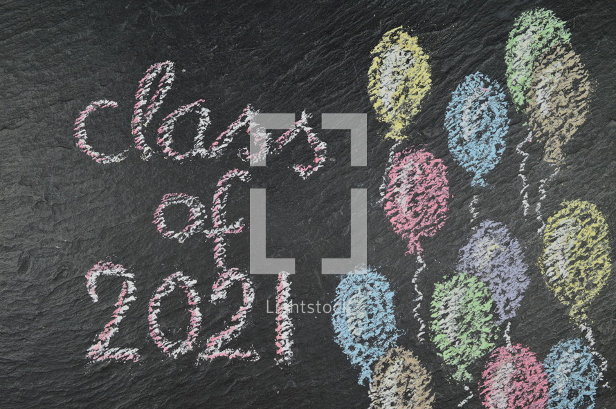 chalk on slate with balloons and the words: class of 2021