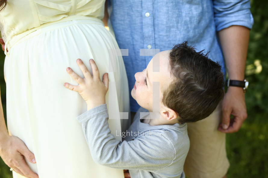 a boy touching his mother's pregnant belly 