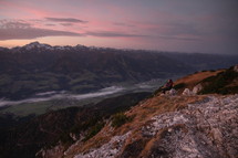 woman sitting on a mountaintop enjoying the views at sunrise 