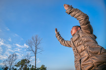 a man in a coat with hands raised 