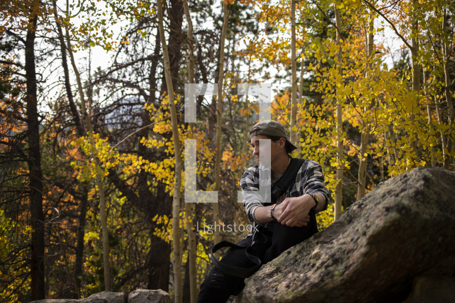 a man sitting on a rock in an autumn forest 