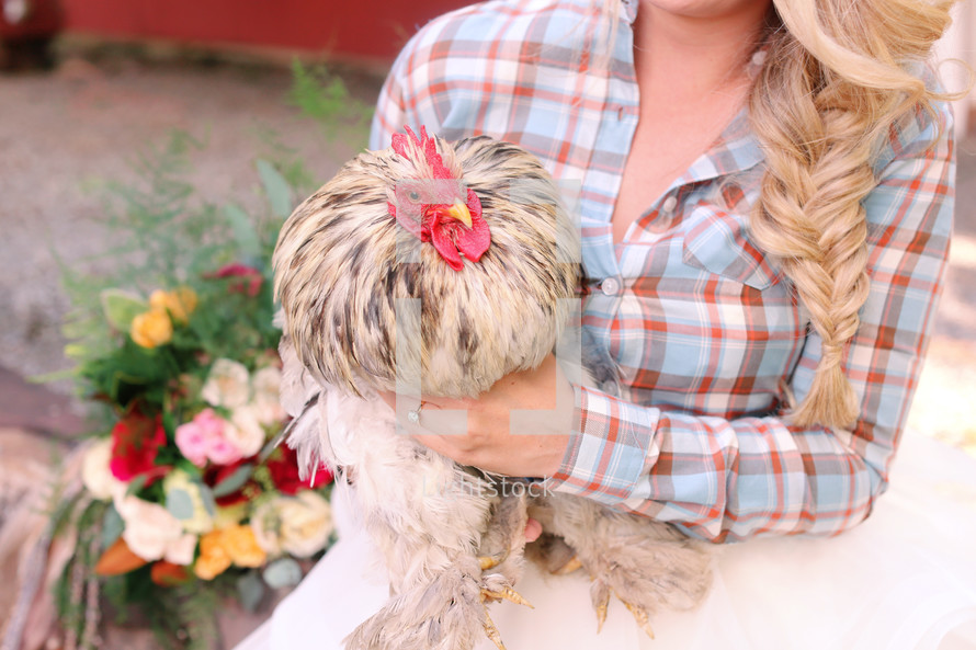 a woman in a plaid shirt holding a chicken 