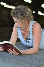 a homeless woman reading a Bible under an overpass