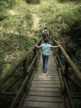 Father and son walking over a wooden bridge,
