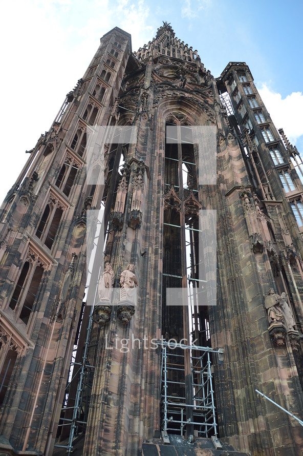 slim tower of a Gothic cathedral.
cathedral, old, Gothic, Gothic age, Gothic style, Gothic period, gothically, Europe, sandstone, freestone, brownstone, ogive, pointed arch, tower, exterior, church, roof, steeple, spire, high, copper roof, copper, flying buttresses, tall, slim, slender, gargoyle, waterspout, spout, figure, statues, jamb statues, under construction, sky, clouds