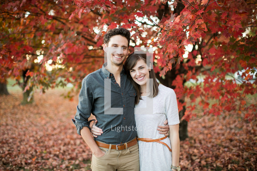 a couple standing together outdoors in fall 