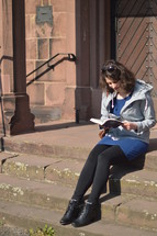 a woman reading a Bible on church steps 