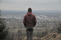 a man standing on a hill looking into the valley