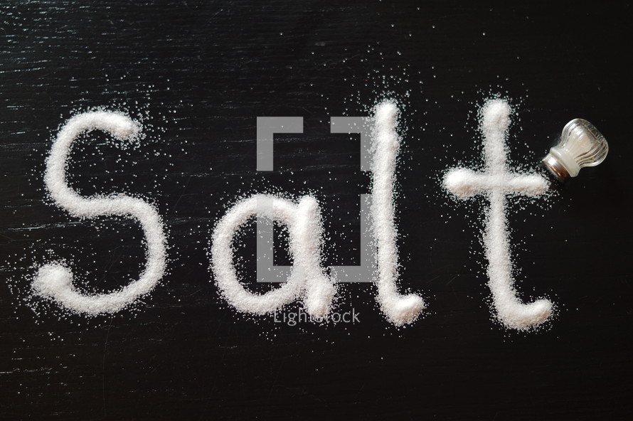 The word, "salt," written with salt on a table.
