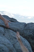 Helping hand to the top of a high rock. 
