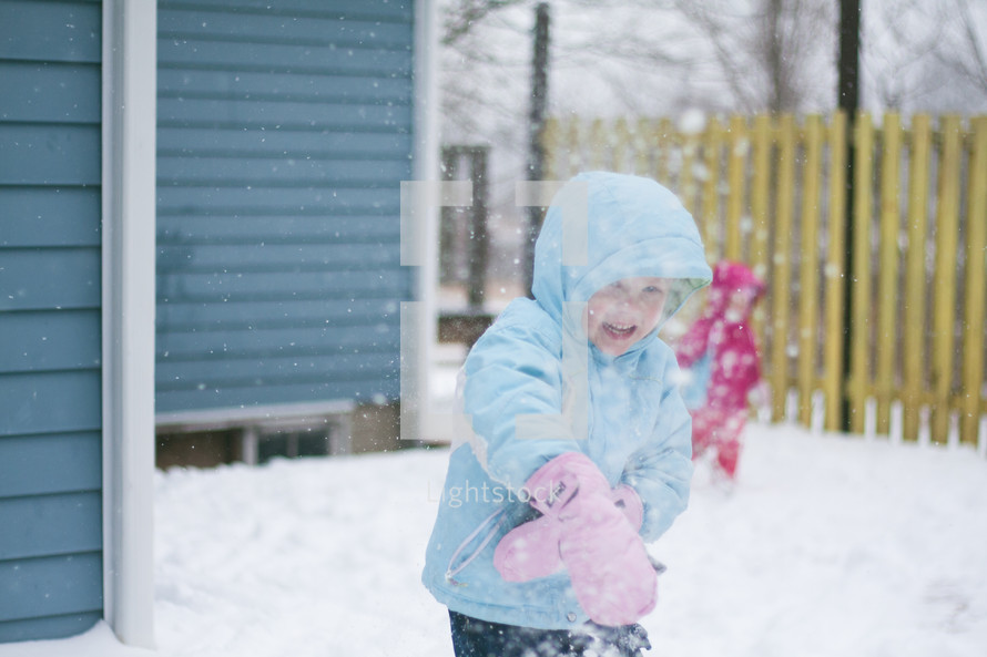 a girl child playing in the snow in mittens 