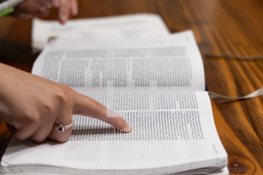 Woman reading Bible during Bible study time in a discipleship group, hands on pages, pointing to verse while reading