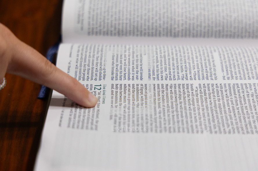 Woman reading Bible during Bible study time in a discipleship group, hands on pages, pointing to verse while reading, close up of verses on page