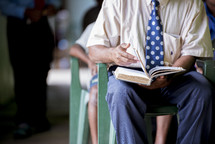 a man sitting reading a Bible during a worship service 