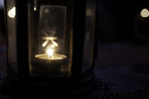 votive candle glowing in a glass lantern
