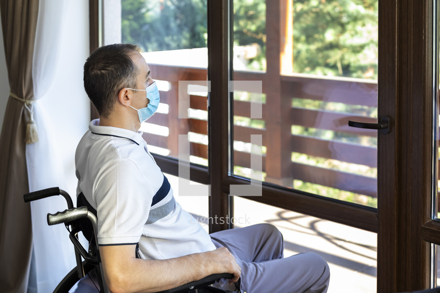 a man in a wheelchair looking out a window 