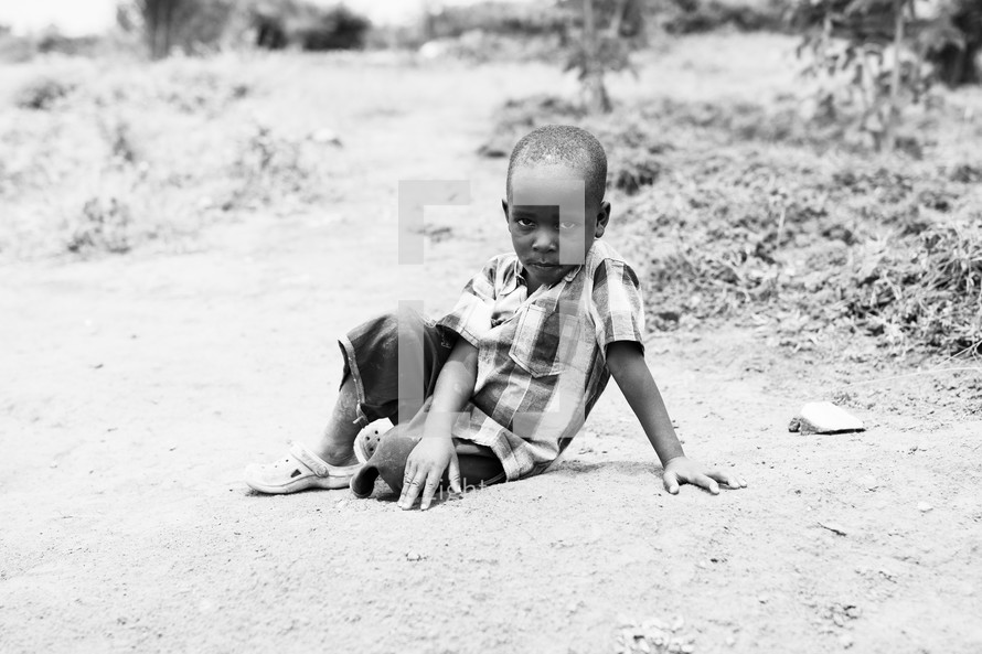 a little boy sitting on the ground 