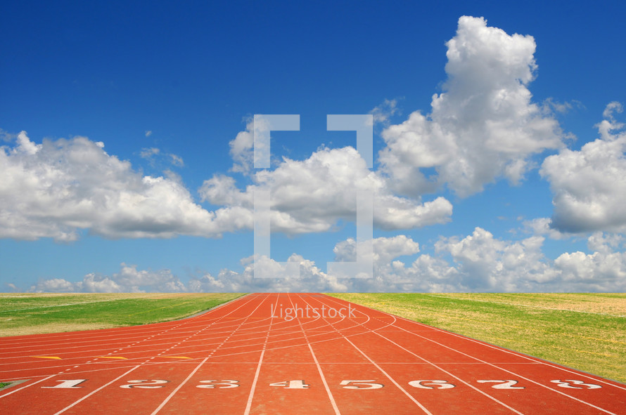 A running track and a blue sky with white puffy clouds.