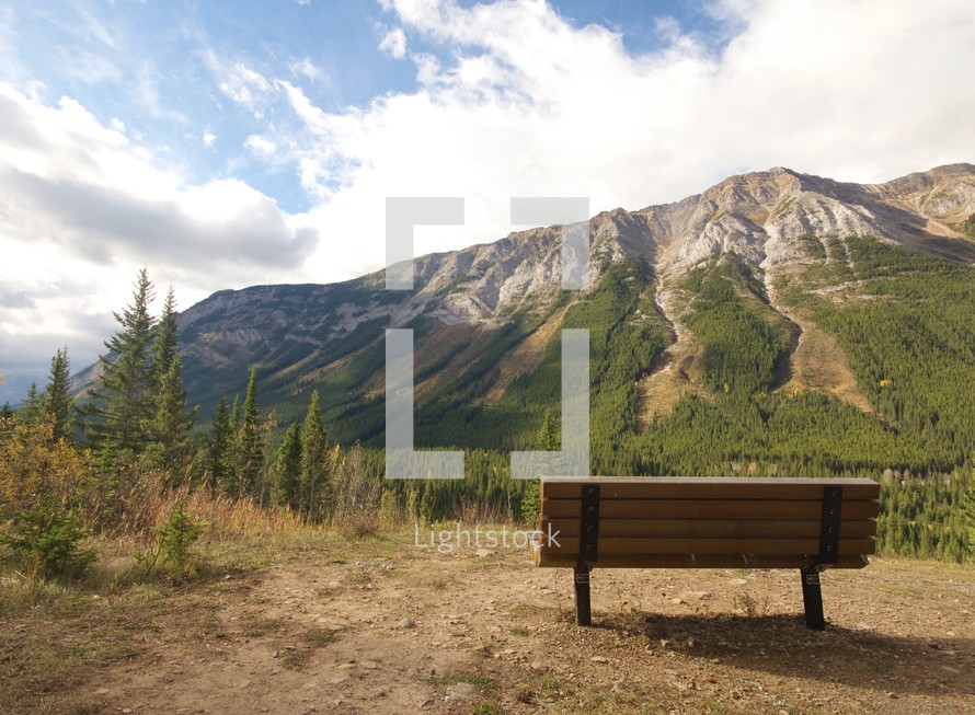 A wooden bench facing a mountain.