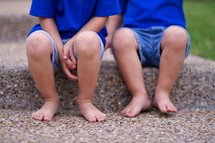 Two barefoot little boys sitting on a step