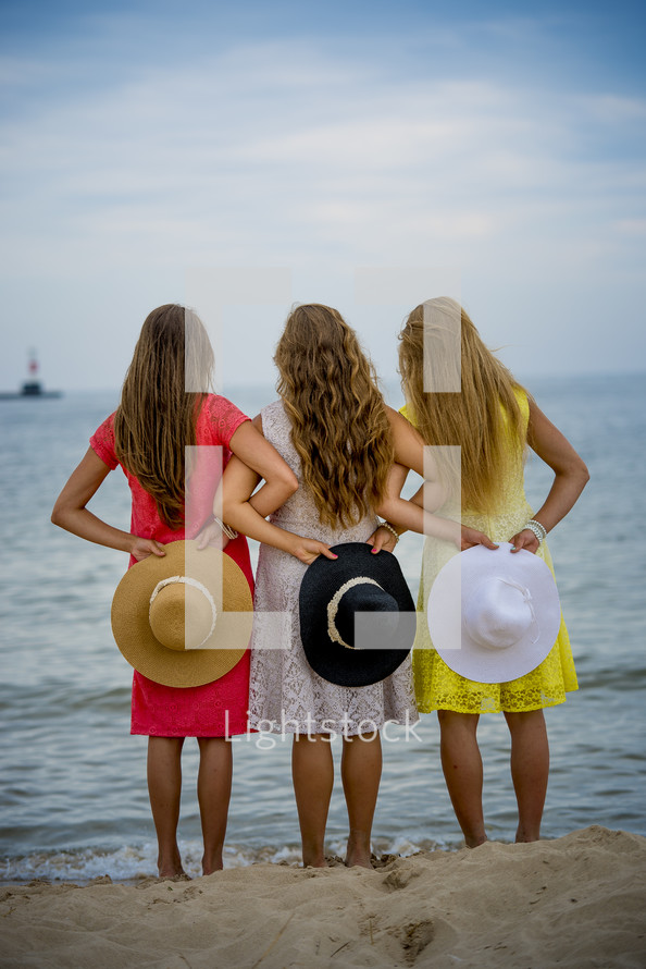 girls holding hat on a beach 