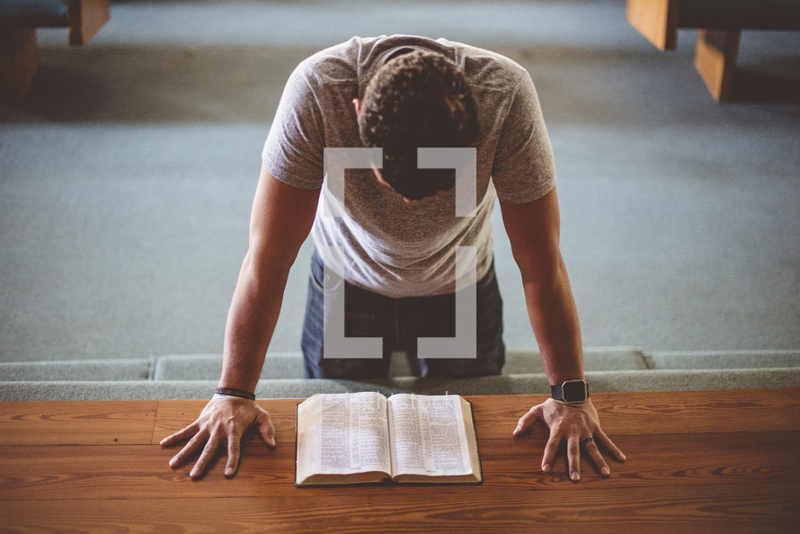 a man kneeling at an altar reading a Bible 