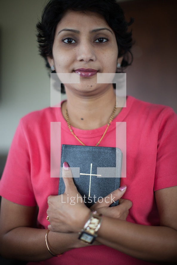 a woman holding a Bible against her chest 