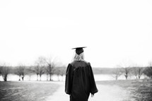 female graduate walking on a dirt road 