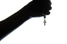 a hand holding a cross necklace 