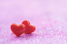 two red hearts on a pink background 