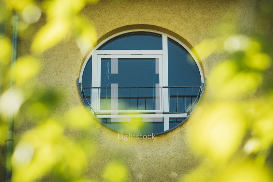 round window surrounded by defocused green leaves 