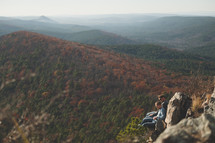 two men sitting on a mountaintop enjoying the view 