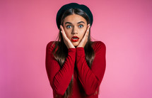 Portrait of cute girl shocked. Pretty woman with perfect make-up, stylish outfit surprised to camera over pink background