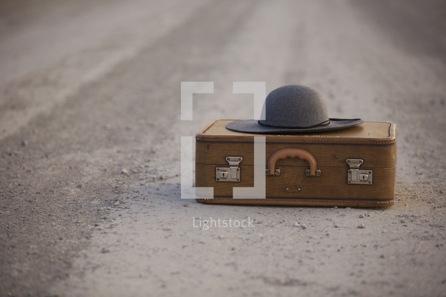 a suitcase and hat on the road