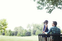 father and daughter sitting on a park bench outdoors 