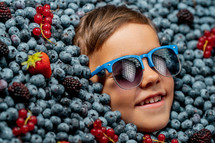 Smiling boy in sunglasses surrounded by berries