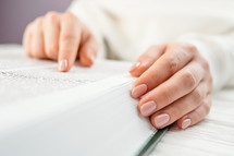 Unrecognizable woman reading big book Holy Bible 