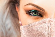 Woman's face in glitter protective mask and eye make-up. 