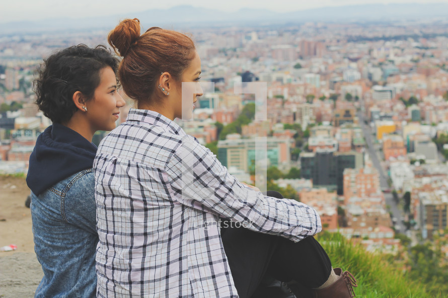 women taking in the view of a city below 