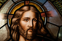 Close up of a stained glass window of Jesus's face and eyes,