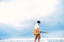 a man with a guitar on a beach 