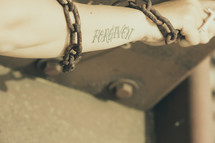 forgiven tattoo on a shackled arm