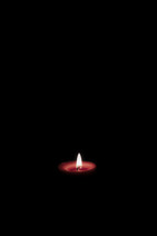 Lit candle in dark room