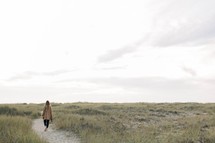 a woman walking on a sandy path 