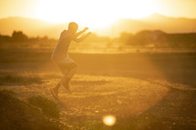 teen boy leaping in warm sunlight 