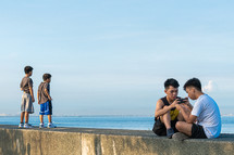 kids on a concrete wall looking out at the ocean 